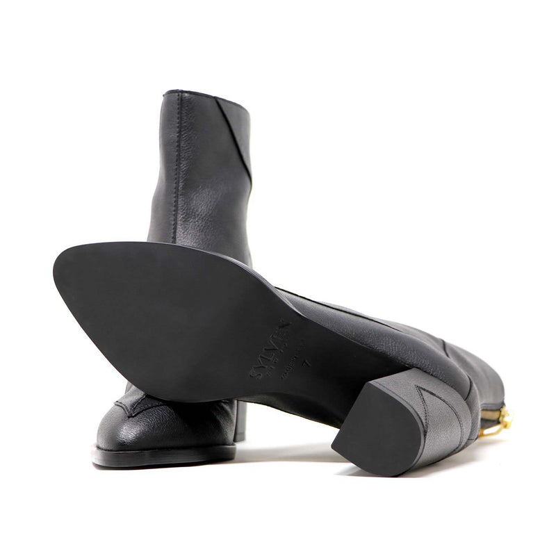 Sylven Almasi Black vegan apple leather boots - one shoe upside down shot